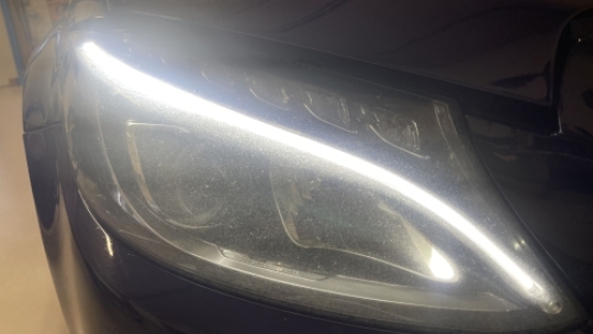 Mat og sløret forlygte før polering på sort bil